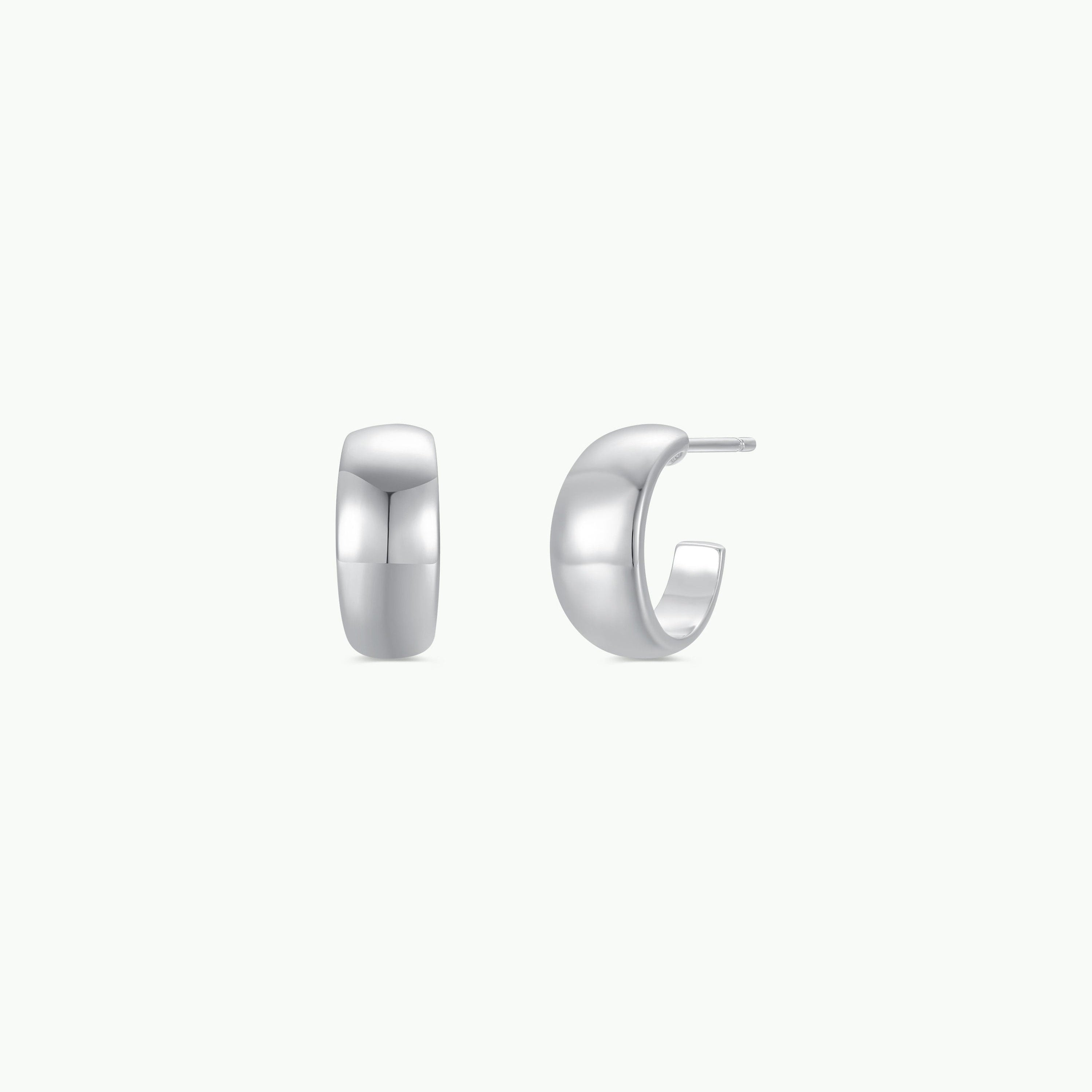 The Silver Wide Hoop earrings are small, chunky hoops with smooth, polished surfaces and sterling silver posts, displayed from the front and side on a plain white background.