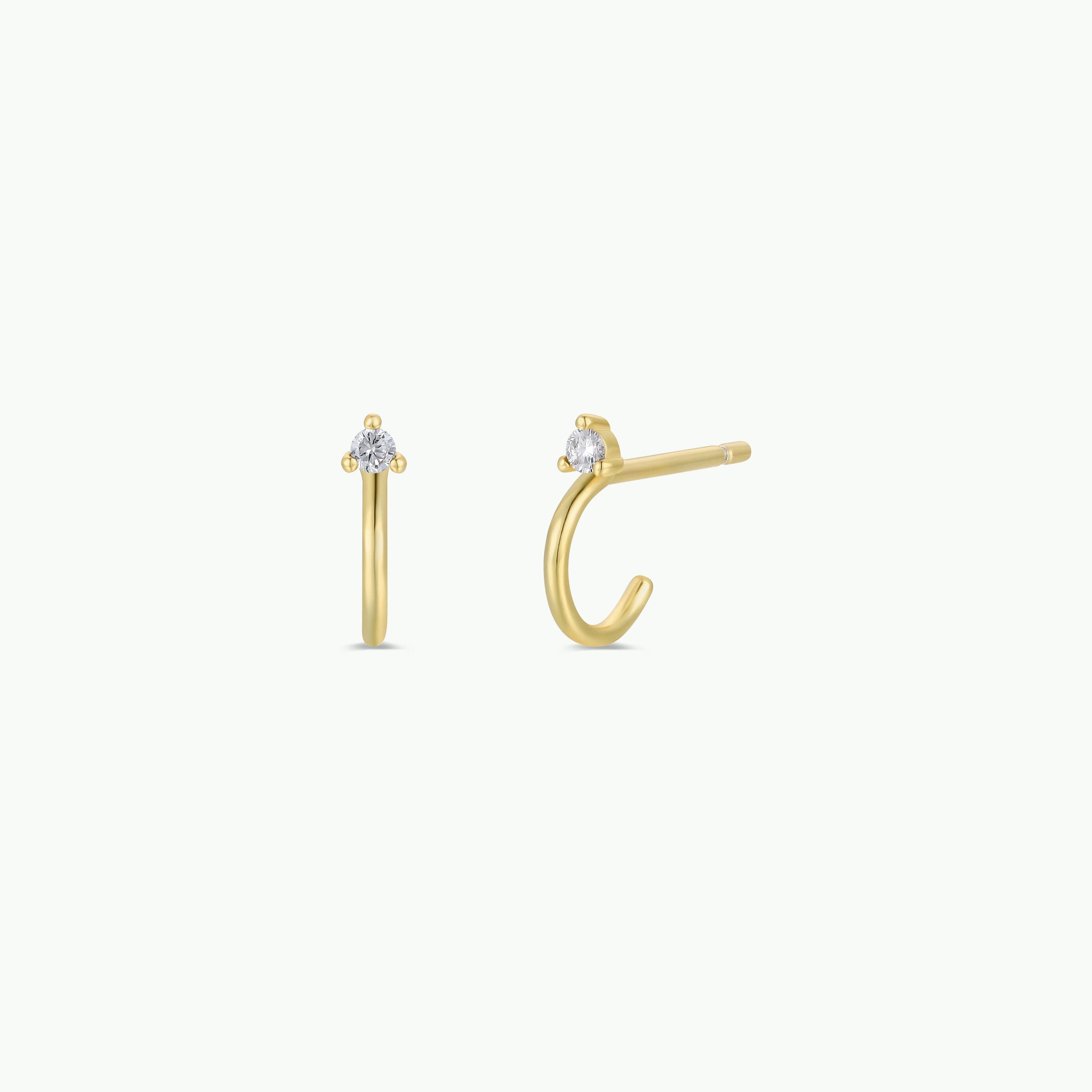 Open Mini Hoop Earring - White: A pair of small gold-plated hoop earrings with a clear round gemstone in a three-prong setting, displayed from front and side views against a plain white background.