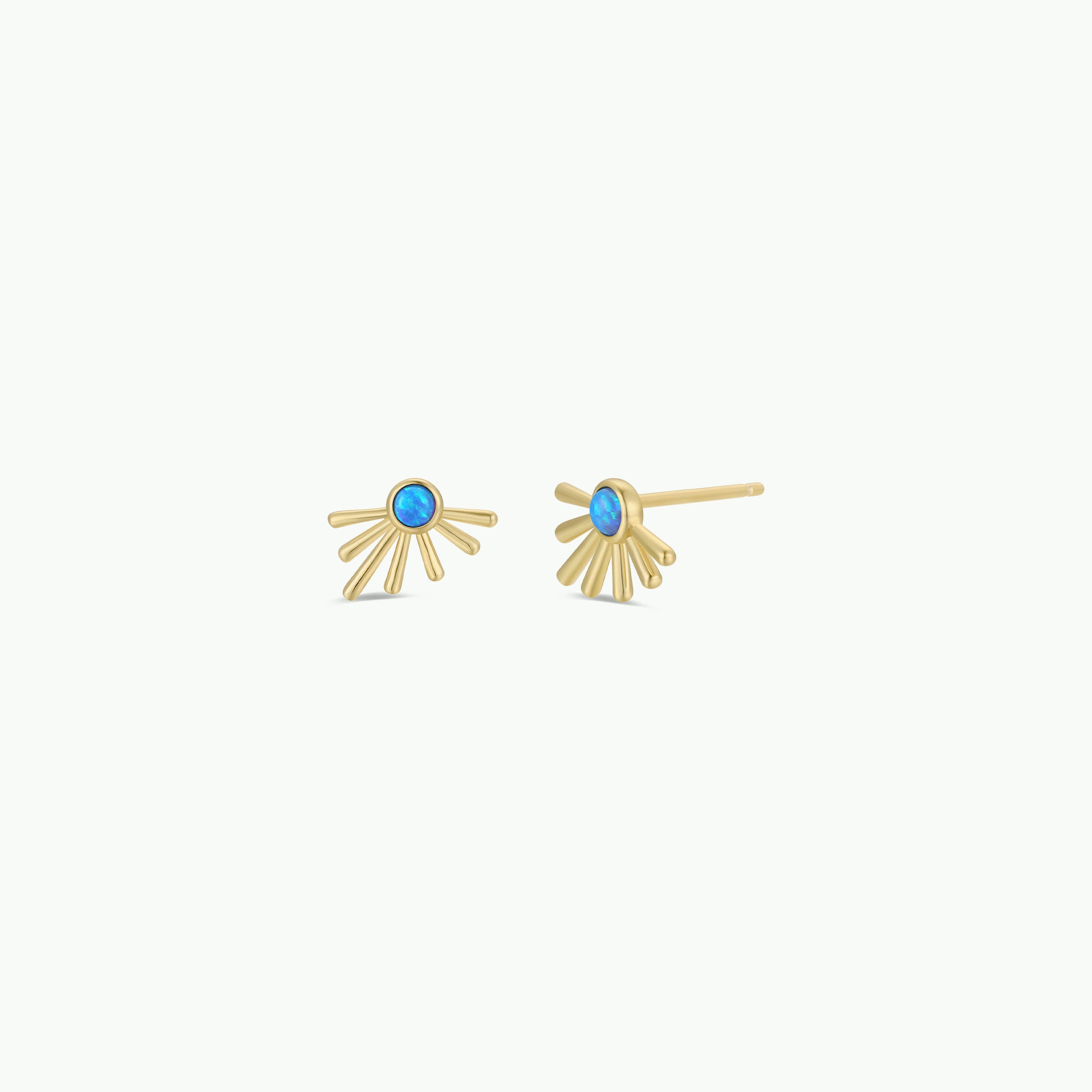 The "Sun Ray - Fire Opal" earrings feature gold studs with a blue circular lab-grown Fire Opal center and fan-shaped 18k gold-plated accents, shown against a plain white background.