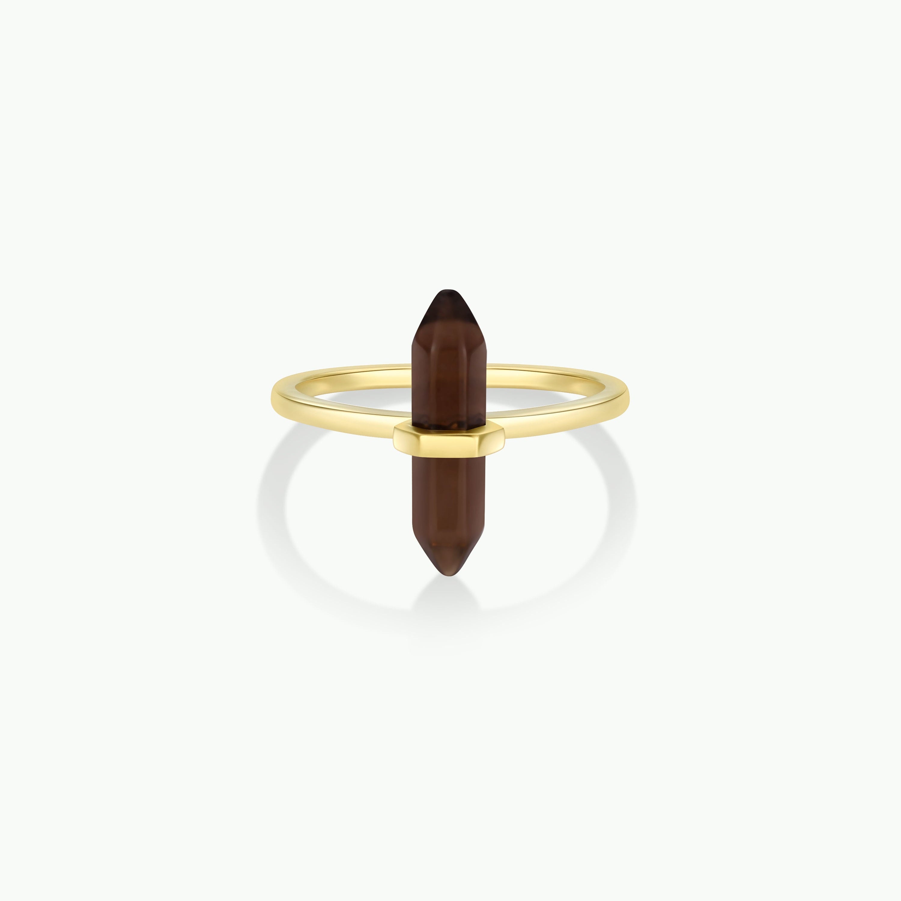 The Smoky Quartz Point Ring showcases a gold band with a vertically set, double-terminated smoky quartz crystal. Displayed on a plain white background, it’s an elegant pick for minimalist jewelry lovers.