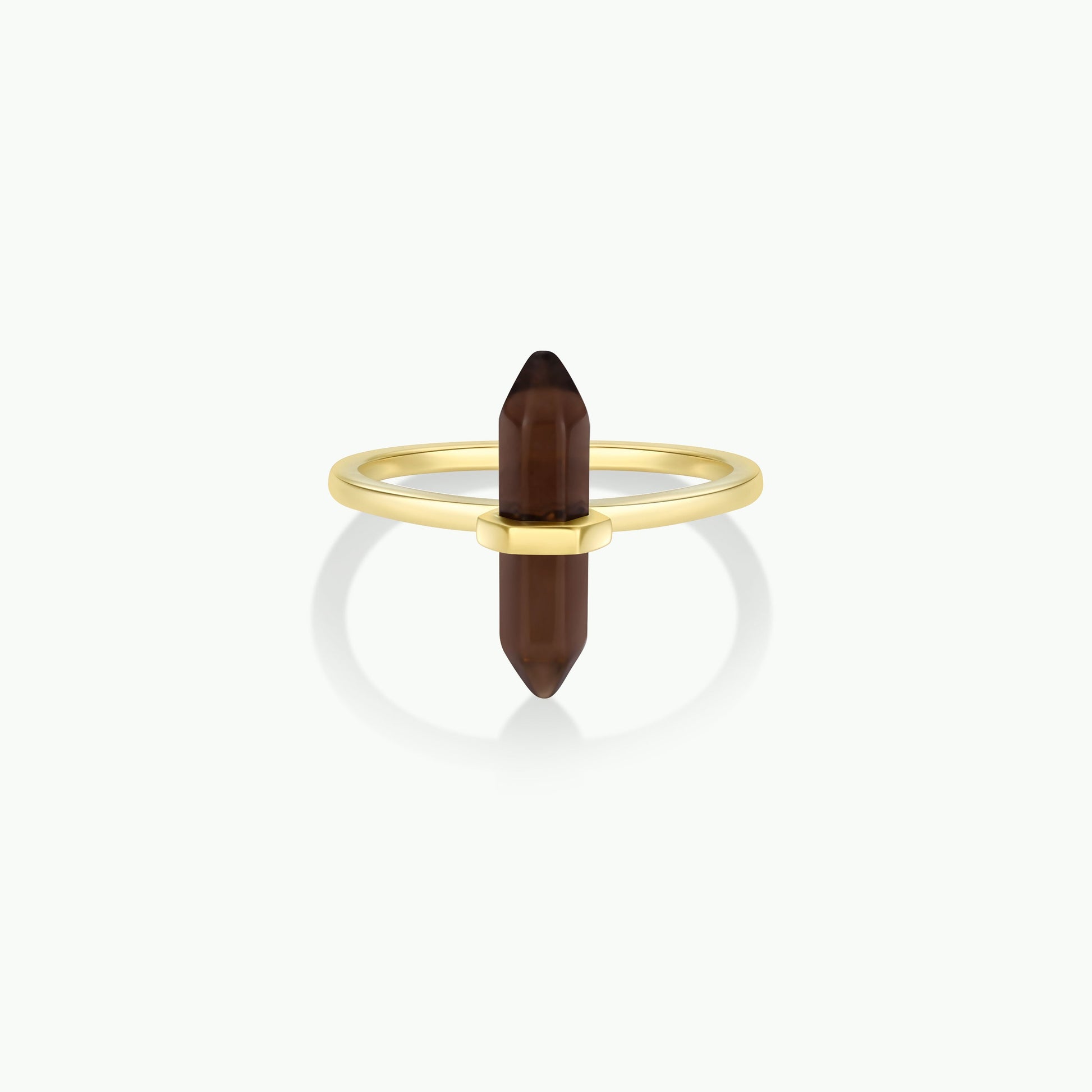The Smoky Quartz Point Ring showcases a gold band with a vertically set, double-terminated smoky quartz crystal. Displayed on a plain white background, it’s an elegant pick for minimalist jewelry lovers.