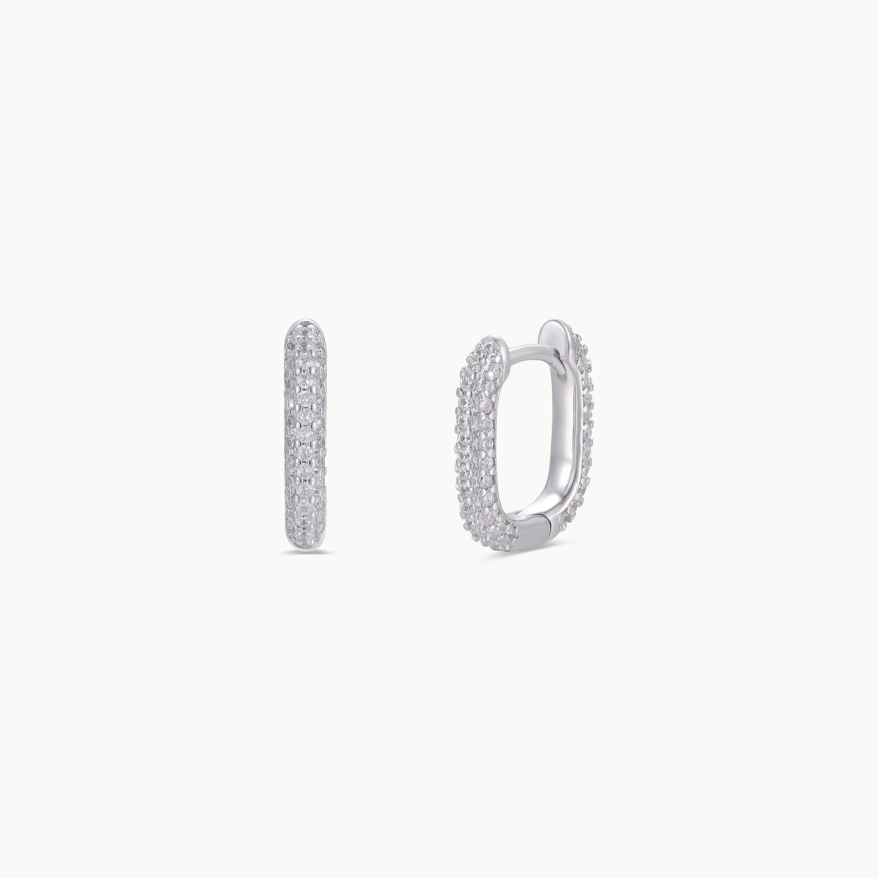 The Pavé Silver Hoop is a pair of small, square earrings encrusted with sparkling white pave CZ stones, crafted in rhodium-plated jewelry and displayed on a plain white background.