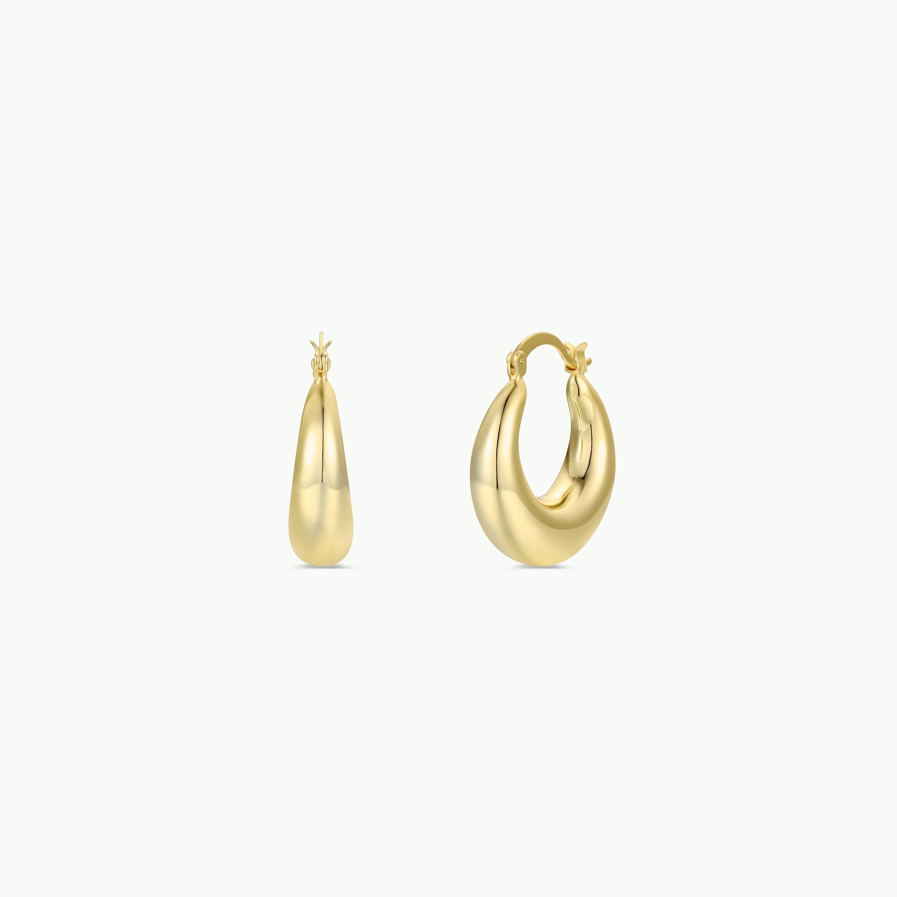 The Sculptural Wide Hoop - Earring features shiny gold plating and a thick, rounded design. Shown on a plain white background, these bold yet lightweight hoops display one earring open and the other closed.