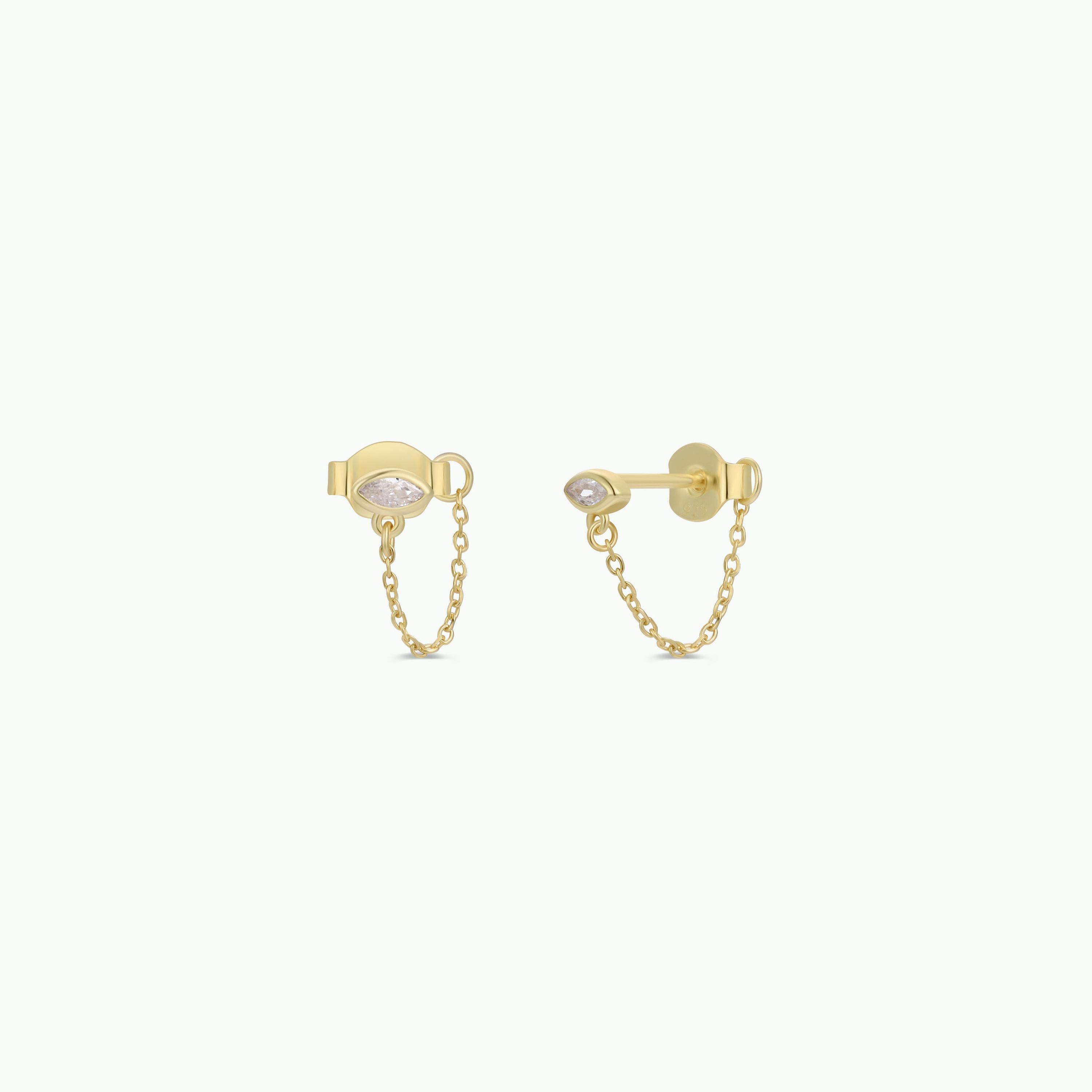 The Stud Chain Huggie features 18k gold-plated studs with small white CZ stones, joined by a delicate gold chain and showcased on a simple light background.