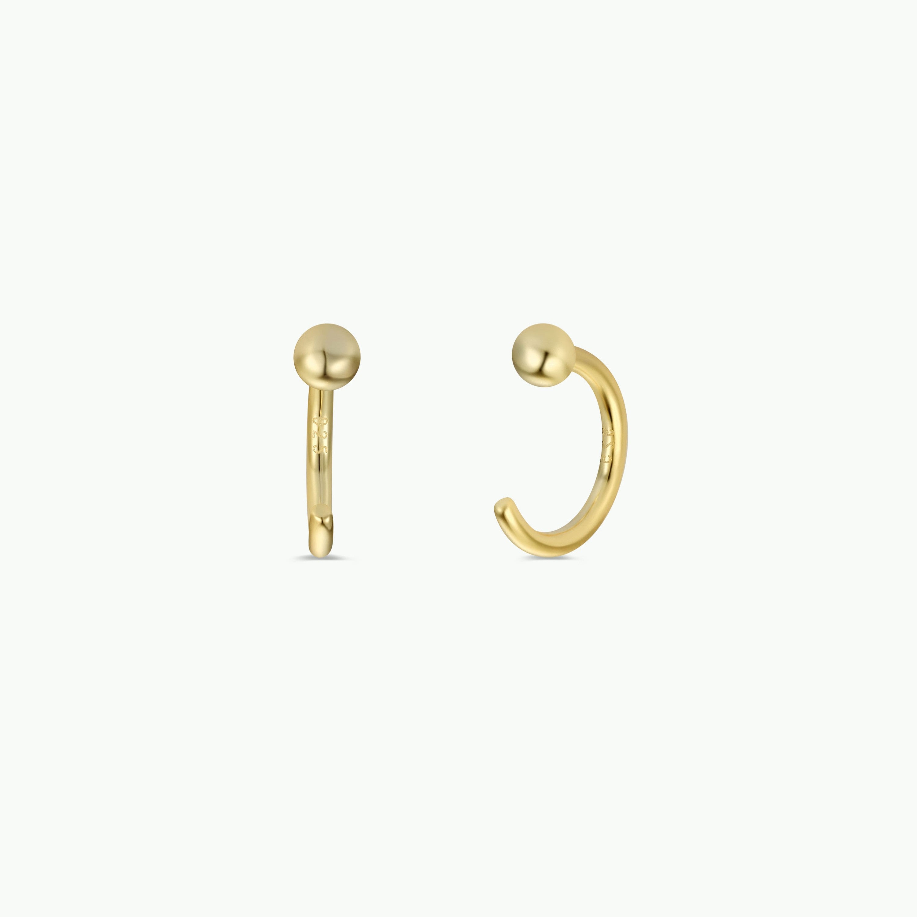 Gold Sphere Huggie: Minimalist 18k gold-plated hoop earrings featuring a small gold ball accent. One earring is displayed front-facing, the other from the side, both set against a plain white background.