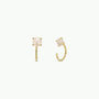 The Mother of Pearl Huggie features gold huggie earrings with round, blush-colored stones in four-prong settings. These dainty, open-ended earrings have stones at the front and are shown against a plain white background.