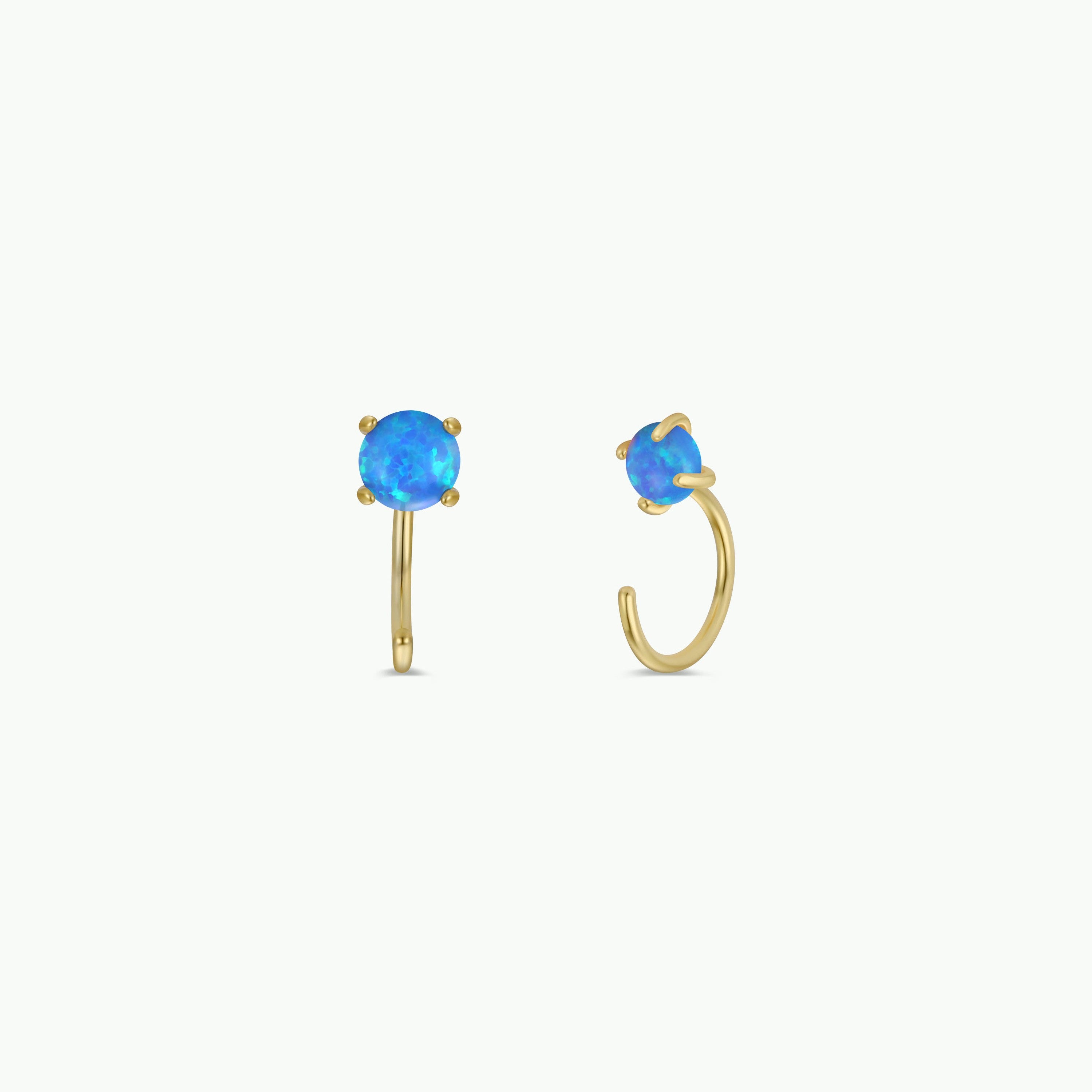 The Fire Opal Huggie is a pair of small gold-plated earrings, each showcasing a round lab-grown Fire Opal in a four-prong setting, displayed on a plain white background.
