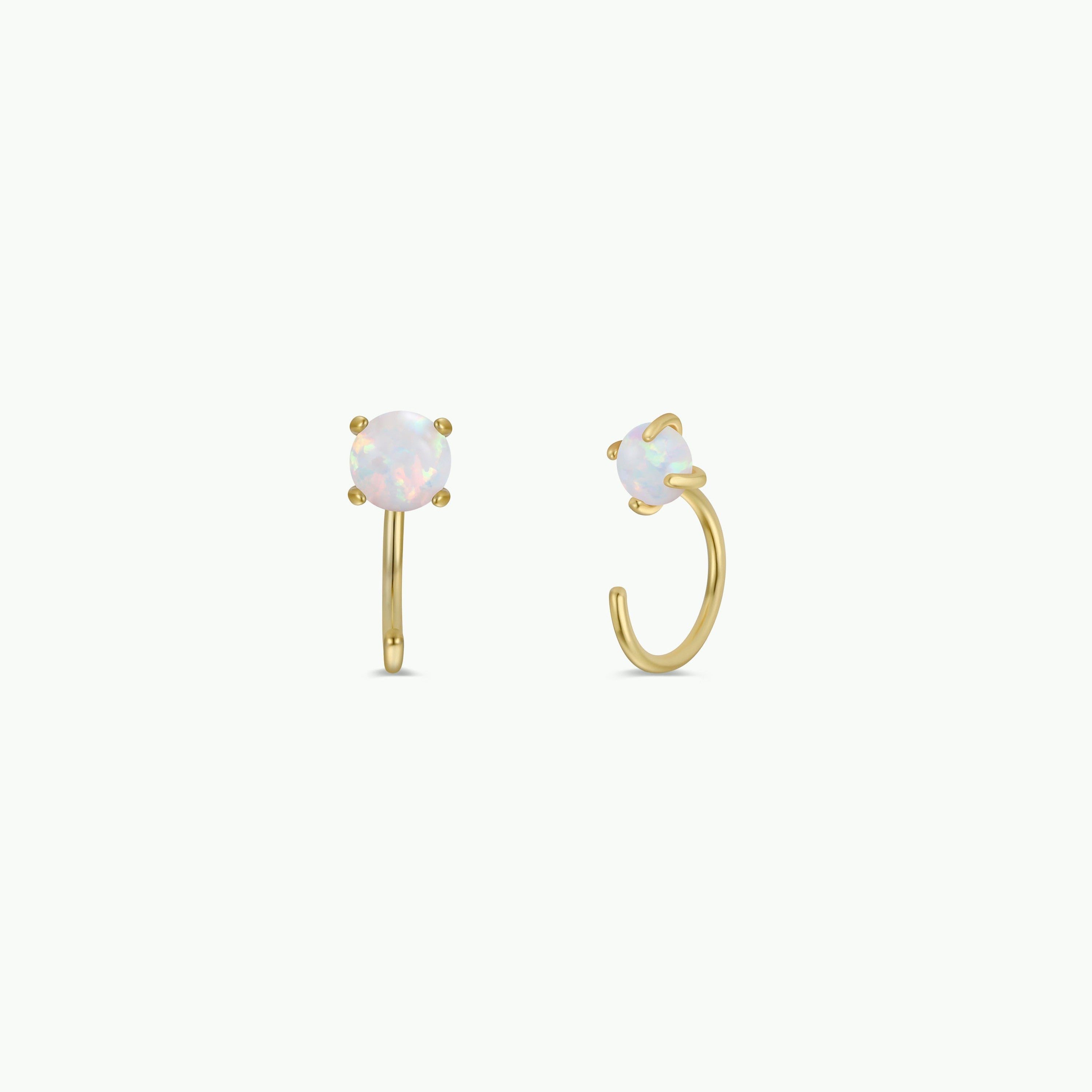 The White Opal Huggie is a pair of gold-plated earrings featuring round, iridescent lab-grown opals in four-prong settings, shown on a plain white background.