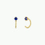 Sapphire CZ Huggie earrings featuring gold hoops with small round blue cubic zirconia stones at the top, shown on a plain white background.
