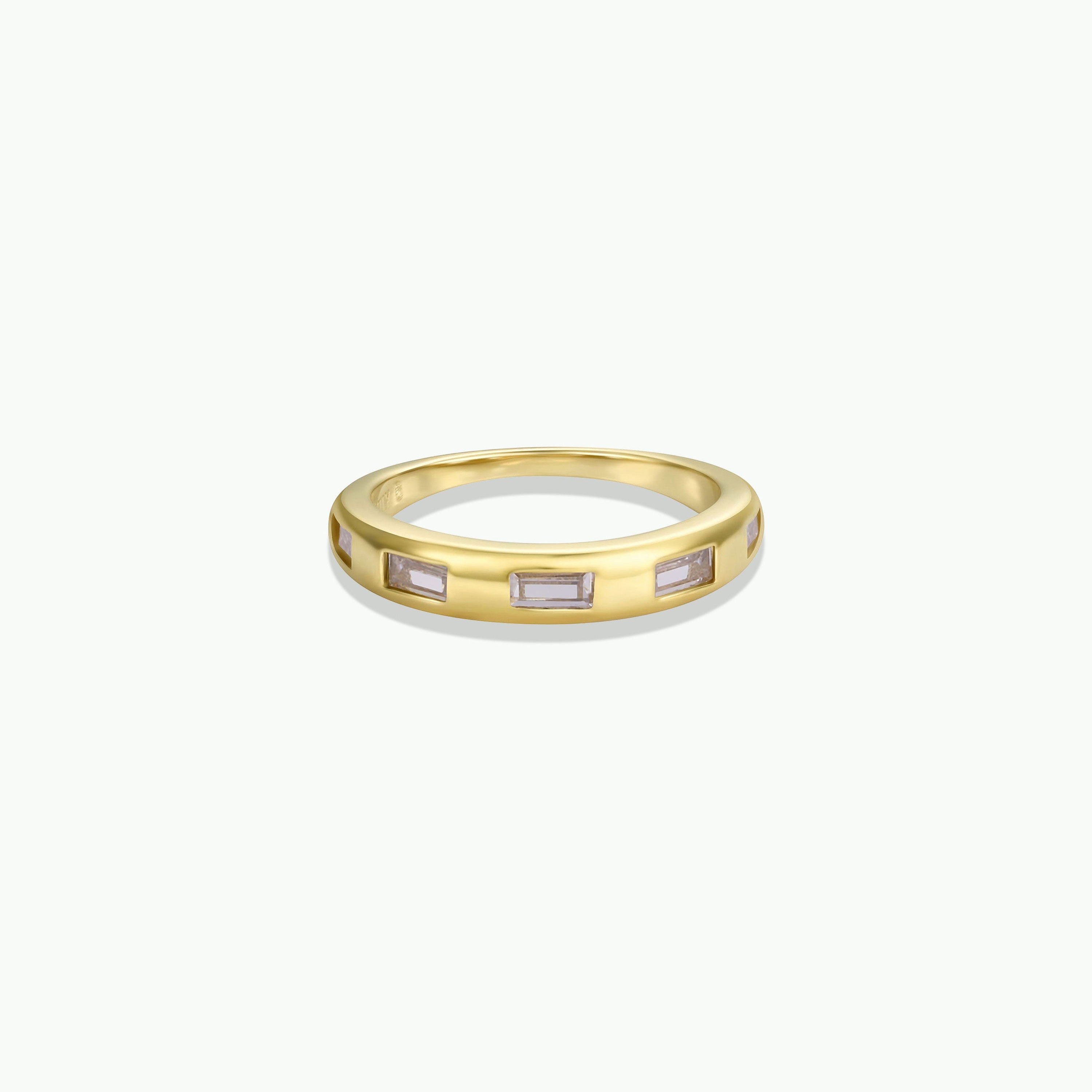 The Inset Baguette Ring features evenly spaced rectangular gemstones set around a gold band, ideal for stacking and shown on a plain white background.