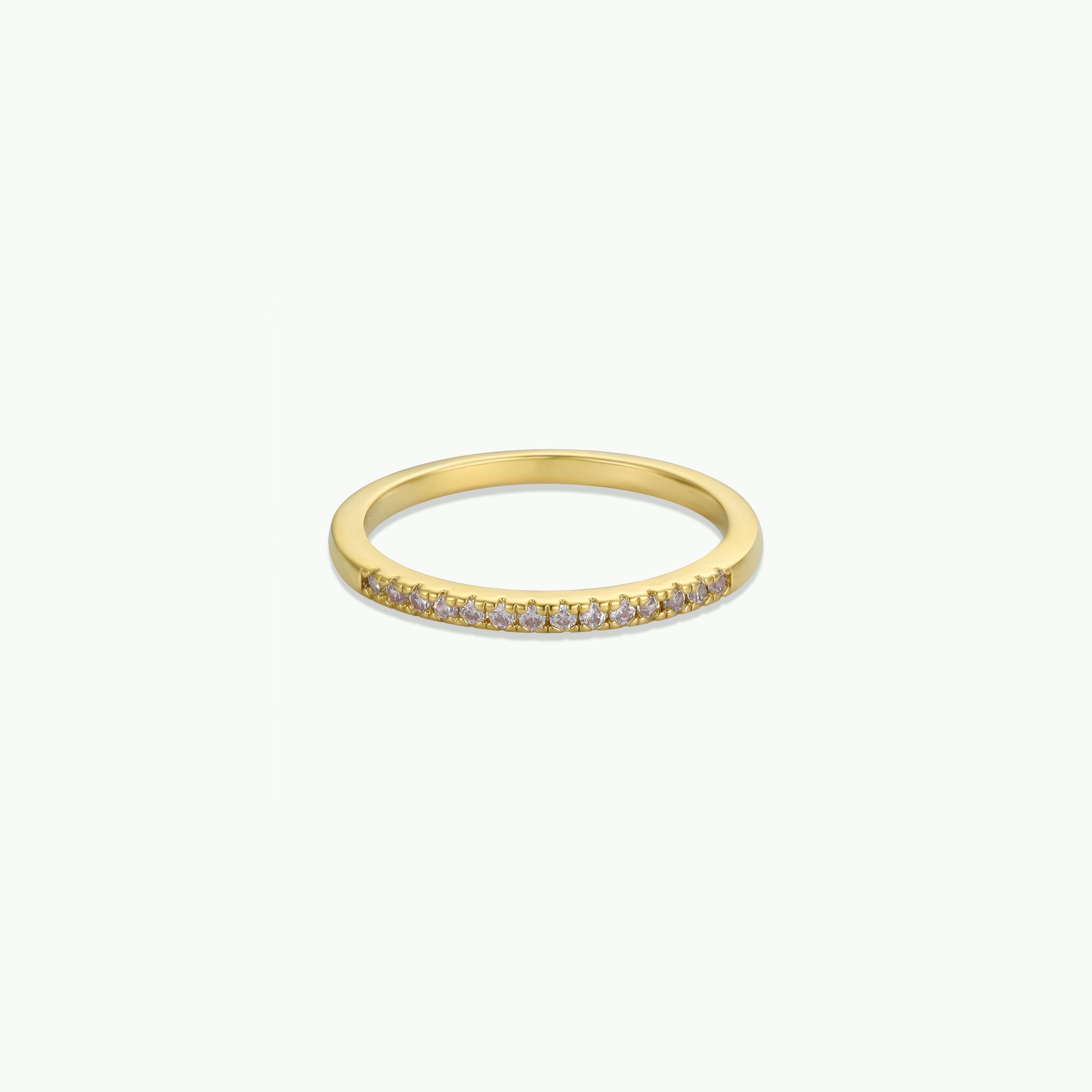 The Half Pavé Ring is a minimalist gold-plated band with a row of sparkling cubic zirconia set along the top, shown against a plain white background.