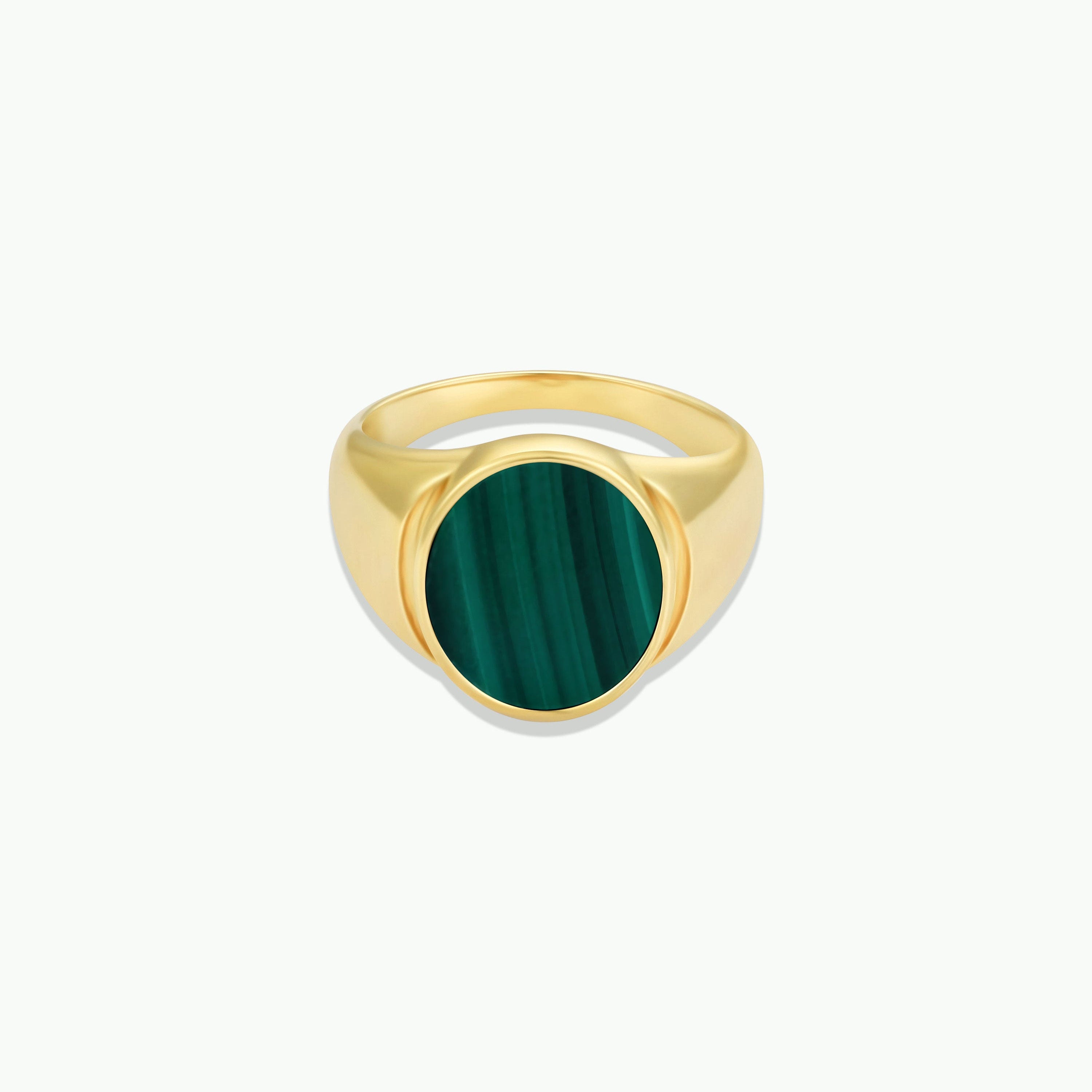 The Malachite Signet Ring features a round, polished malachite stone with natural dark green stripes set at the center, shown on a plain white background.