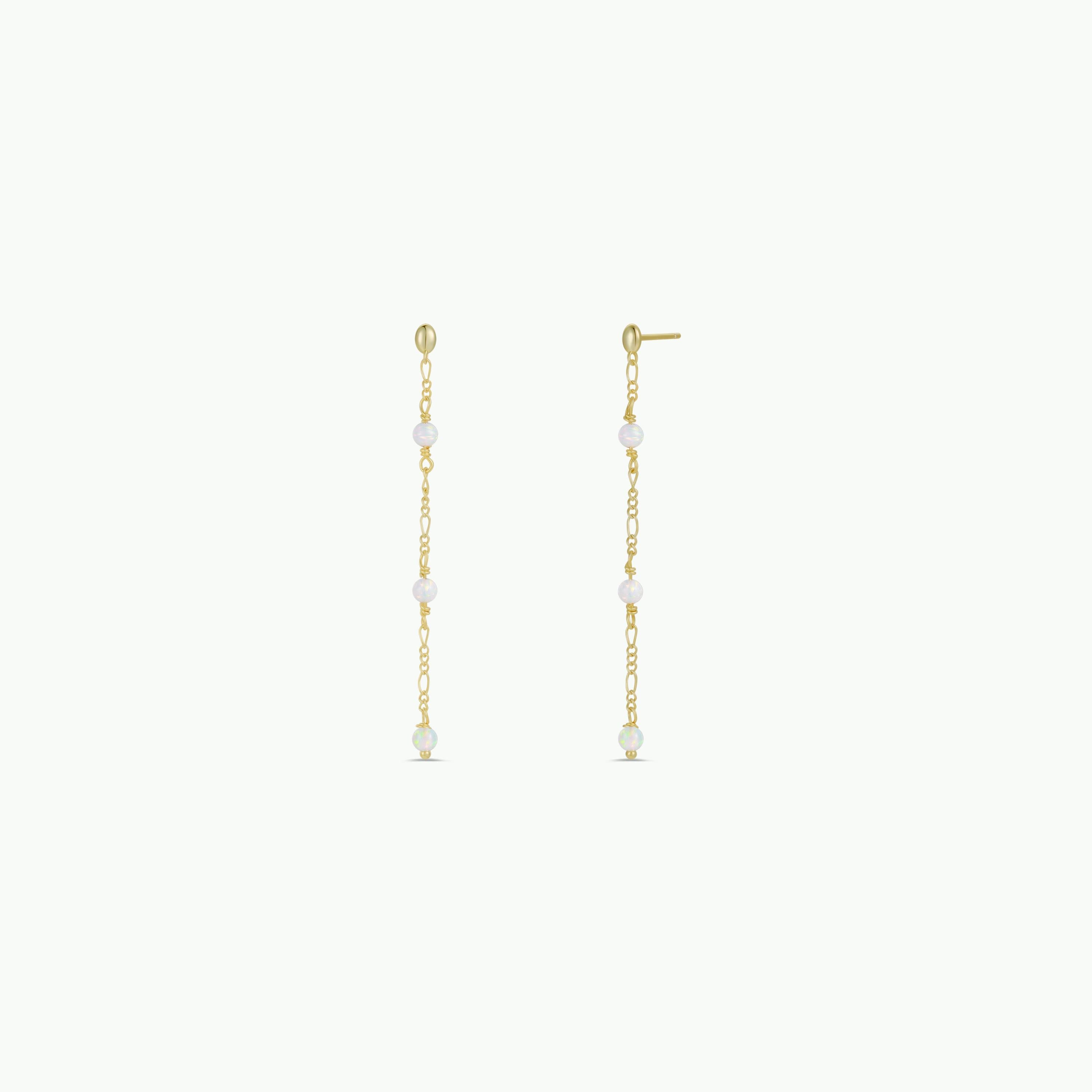 The Gemstone Chain Drop - White Opal earrings feature 18k gold plating and delicate chains adorned with evenly spaced white opal gems, elegantly displayed on a plain light background.