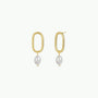 The Oval Pearl Drop features a pair of 18k gold plated elongated hoops with white pearl earrings, beautifully displayed on a plain white background.