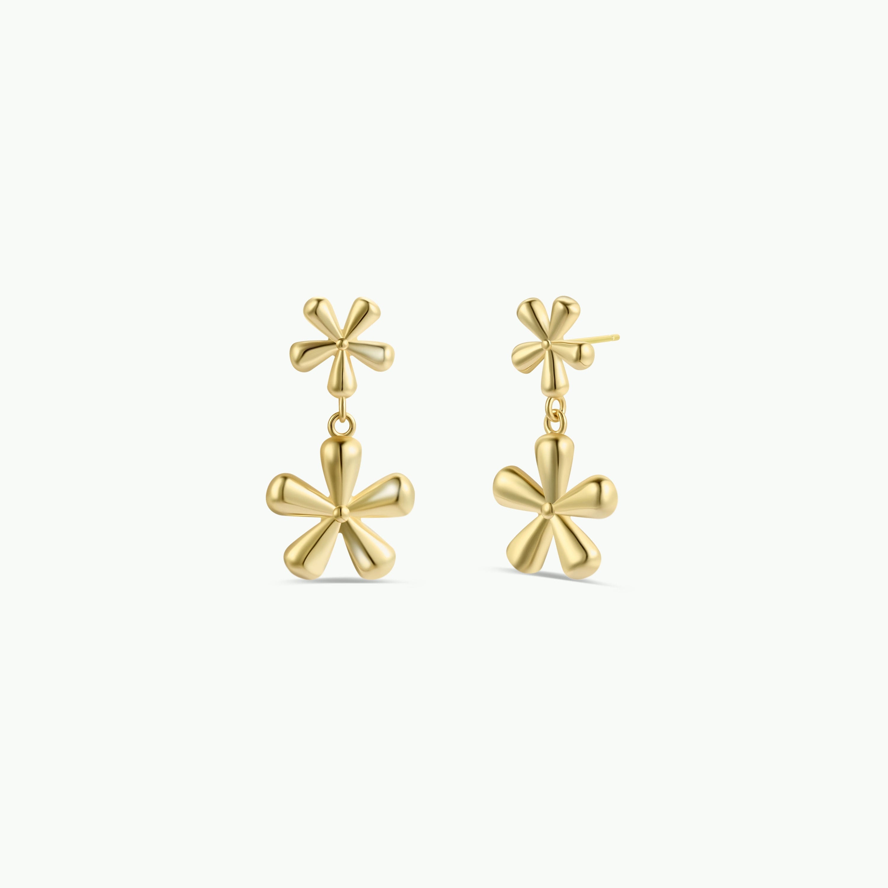 The Double Daisy Drop Earring by JaxKelly features gold-plated, shiny earrings with two rounded-petal daisy designs— a small flower on top and a larger, dangling daisy below.