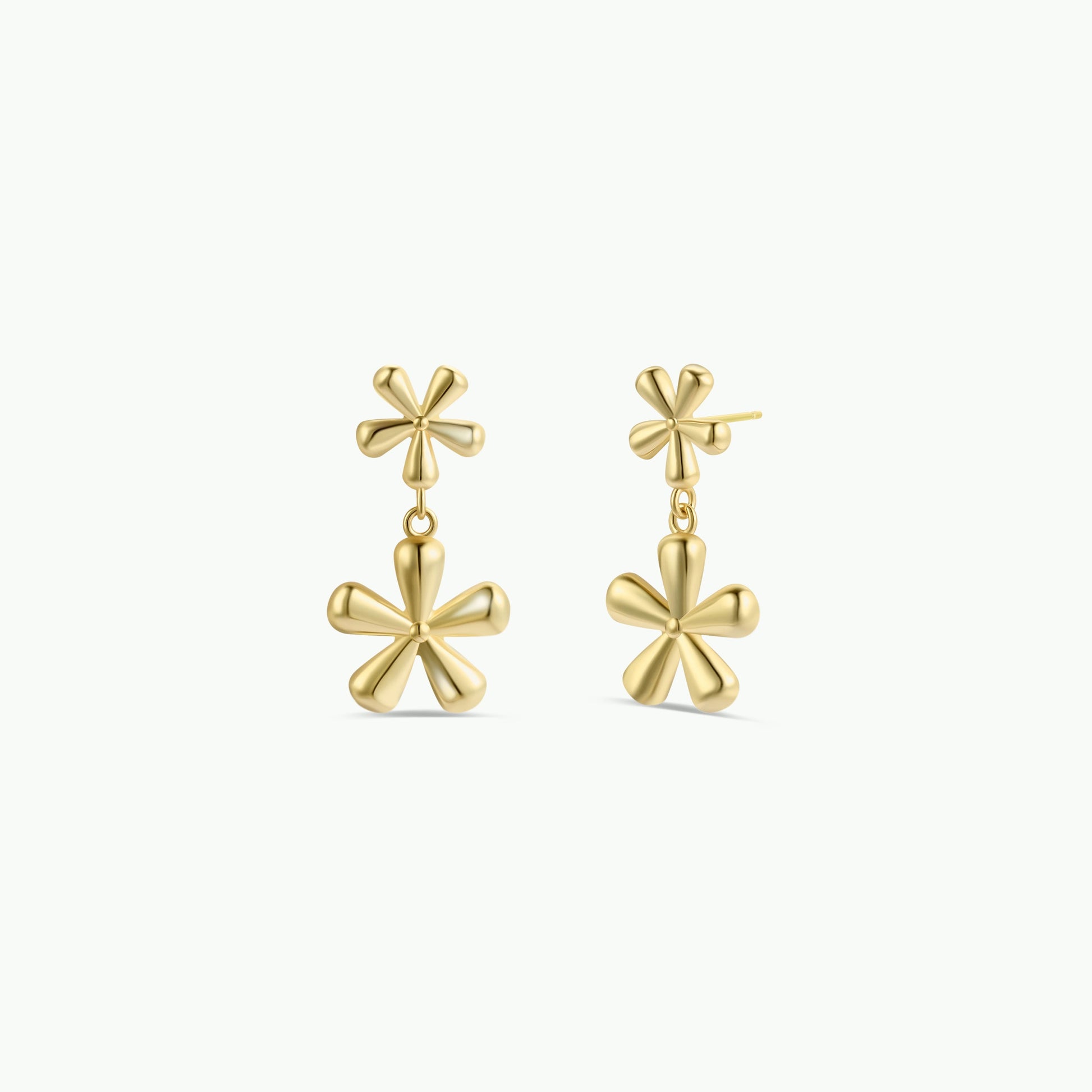 The Double Daisy Drop Earring by JaxKelly features gold-plated, shiny earrings with two rounded-petal daisy designs— a small flower on top and a larger, dangling daisy below.