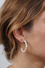 Close-up of a woman's ear wearing Multi Pearl Hoop Earrings with irregular freshwater pearls and a gold stud. Her light brown hair falls in loose waves.