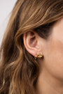 Close-up of a woman's ear with wavy brown hair, wearing the Double Hoop - Earring featuring one gold-plated hoop and a small textured stud.