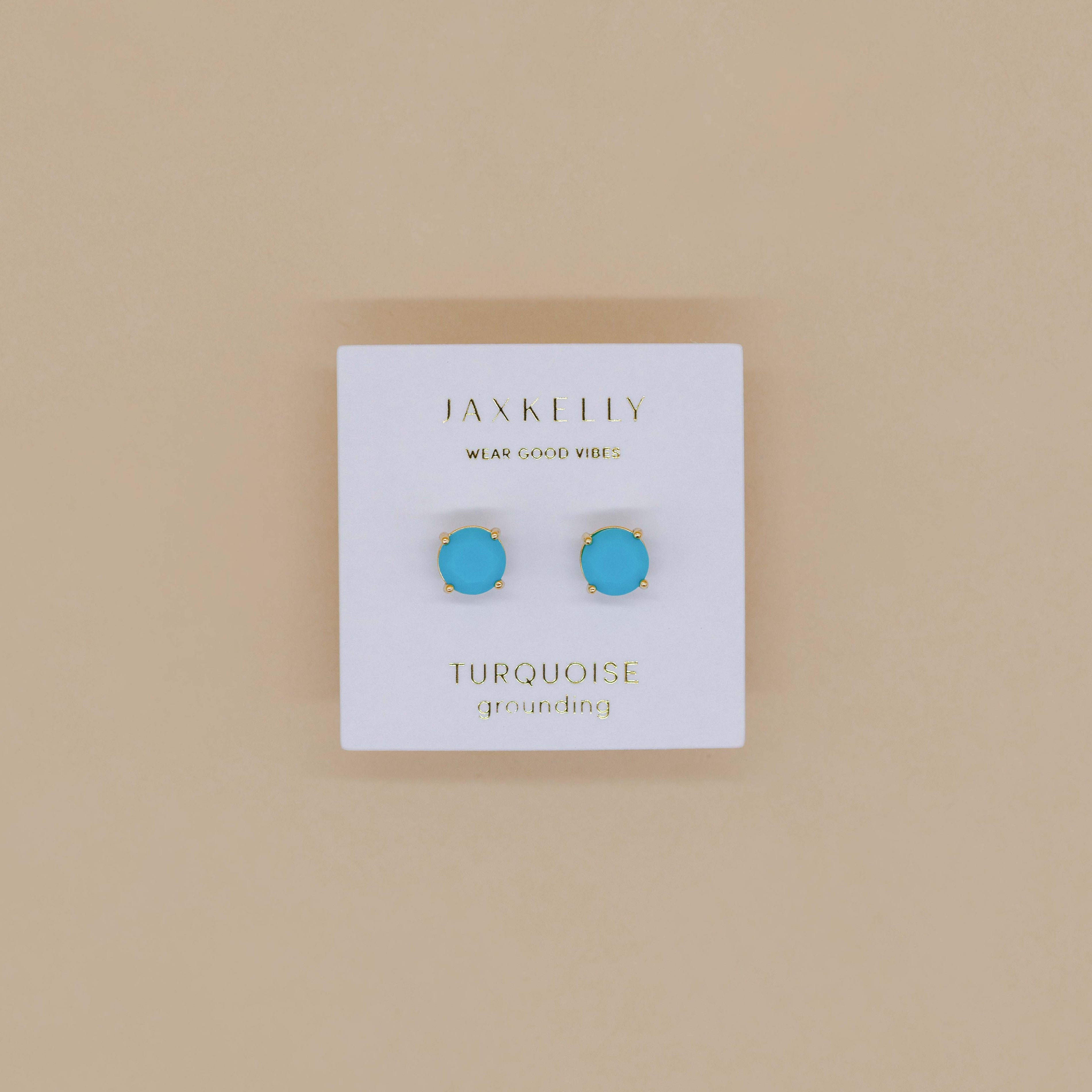 A pair of Round - Turquoise Gemstone- Gold Earrings is displayed on a white JaxKelly Wear Good Vibes and Turquoise Grounding card against a beige background.