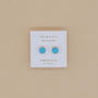 A pair of Round - Turquoise Gemstone- Gold Earrings is displayed on a white JaxKelly Wear Good Vibes and Turquoise Grounding card against a beige background.