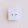 A pair of Offset Trio - Sapphire CZ earrings by JaxKelly displayed on a white card with the brand name. These small hypoallergenic sapphire CZ studs are perfect for sensitive ears.