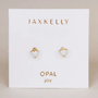 A pair of Tiny White Opal Heart studs by JaxKelly, featuring lab-grown opal in heart shapes, gold plated and displayed on a white card labeled “OPAL joy.”.