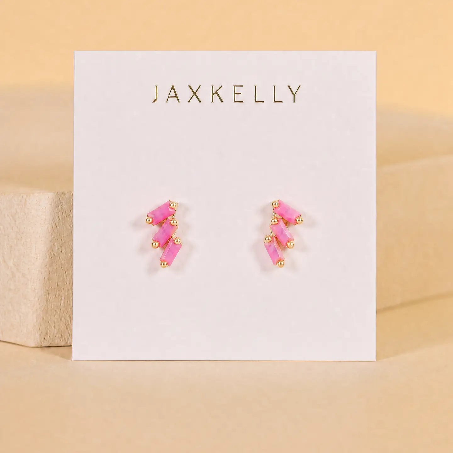 Offset Trio - Pink Opal by JaxKelly: gold plated hypoallergenic stud earrings featuring pink rectangular stones, shown on a white JaxKelly card against a neutral beige background—perfect for everyday elegance.