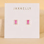 The JaxKelly Pink Opal Baguette earrings feature lab-grown pink opal gemstones in gold prongs, displayed on a white card with gold JaxKelly lettering. Hypoallergenic and perfect for sensitive ears.