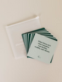 Abundance Shower Affirmations™: Waterproof affirmation cards with abundance quotes, shown beside a translucent pouch—ideal for daily inspiration, even in the shower. Top card: What I focus on is what I manifest.