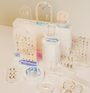 A variety of gold earrings, hoops, studs, and ear cuffs are showcased on JaxKelly displays and Clear Earring Display Stud Arch stands of different shapes and heights against a light background.