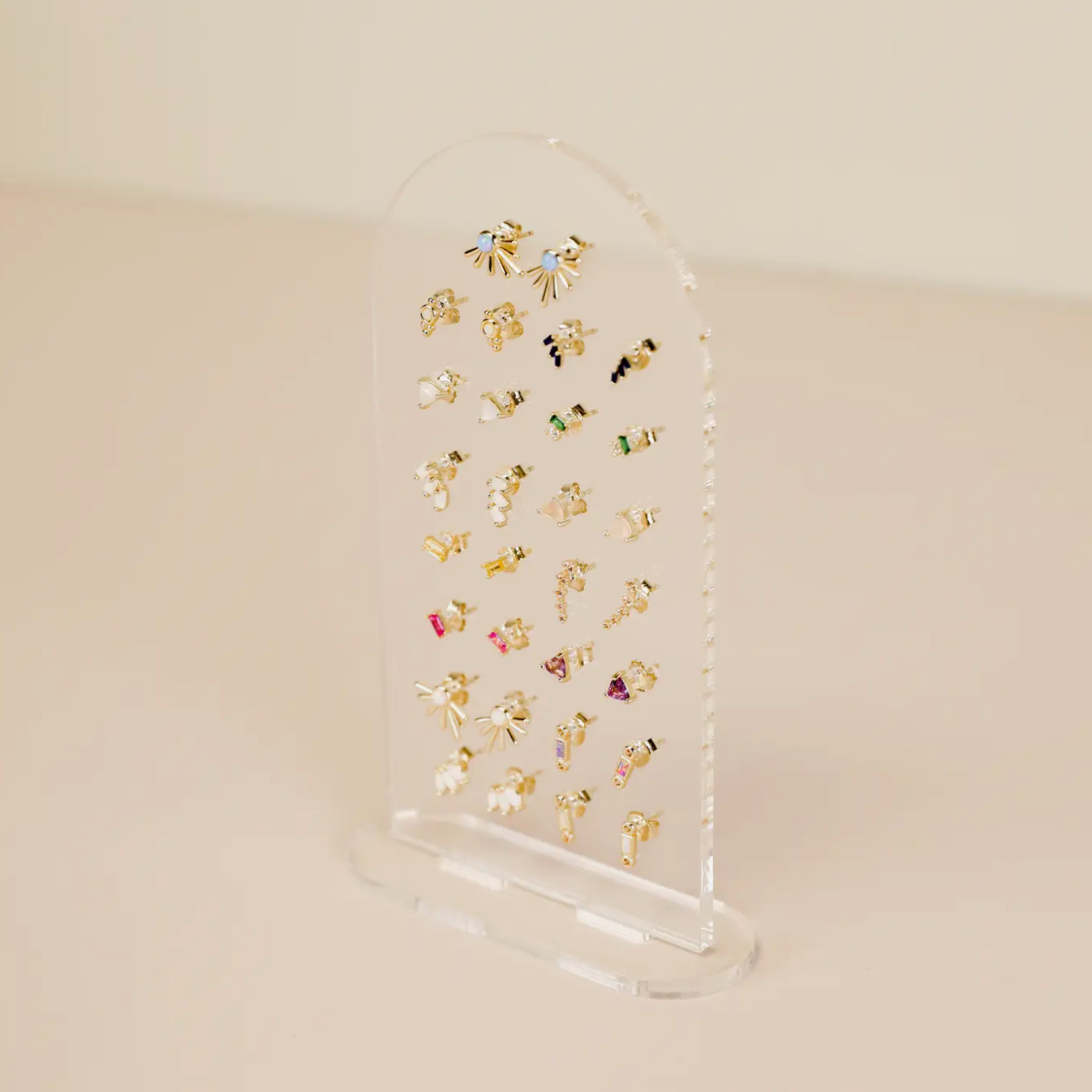 The Clear Earring Display Stud Arch offers an elegant retail display, showcasing stud earrings and small dangles in colorful and gold styles against a neutral background with its clear acrylic design.