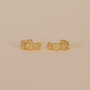 The Petite Flower Hoop earrings, featuring a small, beaded irregular design with 18K gold plating and sterling silver posts, are displayed on a plain beige background, showcasing their elegant and minimalistic style.
