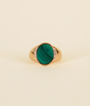 The Malachite Signet Ring features an oval green malachite gemstone set at the center of an elegant 18k gold plated band, displayed against a plain light background.