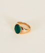 The Malachite Signet Ring showcases a round, polished green malachite in a bezel setting on 18k gold plating, displayed against a plain light background.