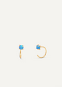 The Fire Opal Huggie features two gold plated earrings, each set with a single round lab-grown Fire Opal in a four-prong setting, shown on a plain white background.