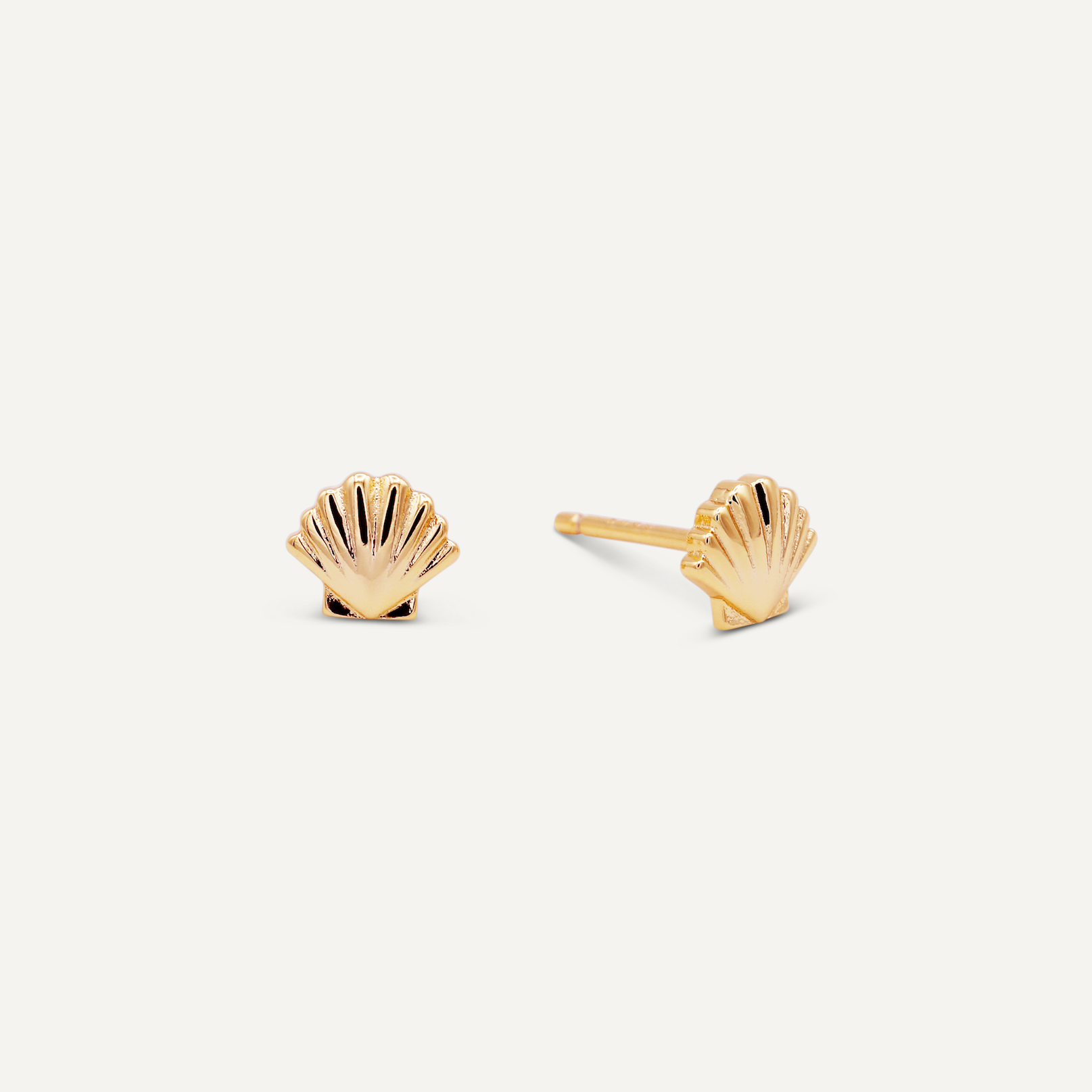 The Seashell Stud - Earring is a pair of hypoallergenic gold stud earrings shaped like scallop seashells, displayed on a plain white background.