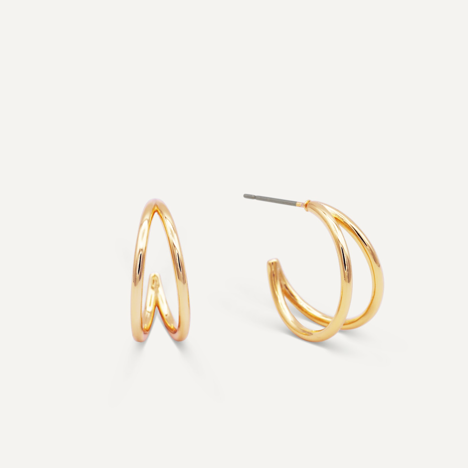 The Illusion Double Hoop - Gold Earrings feature a sleek, modern double-band design in gold-tone. Displayed on a white background, one earring stands upright while the other lies flat to show the post for pierced ears.