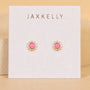The Pink Opal Sun Stud by JaxKelly features gold sun-shaped studs with hypoallergenic posts and pink opal centers, presented on a white card stamped with the JaxKelly logo in gold.