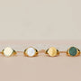 The JaxKelly Malachite Signet Ring is shown with three other 18k gold plated signet rings—each with unique stone inlays (green malachite, white, gold, and dark green)—lined up on a neutral surface against a soft beige background.