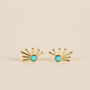 The Sun Ray - Turquoise stud earrings feature a turquoise center and gold-plated rays in a sunburst design, displayed on a neutral beige background.