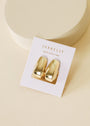 The Bold Drop Earring features shiny gold-plated hoops with sterling silver posts, displayed on a JaxKelly card reading "WEAR GOOD VIBES," set against a neutral beige background.