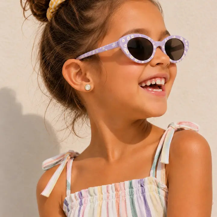 A young girl wearing small, round, hypoallergenic Volleyball Enamel Flat Back Kids Earrings featuring a white and gray striped volleyball pattern.