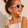 A young girl wearing small, round, hypoallergenic Volleyball Enamel Flat Back Kids Earrings featuring a white and gray striped volleyball pattern.