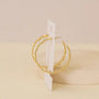 The Daisy Chain Earrings by JaxKelly feature enamel and 18K gold plating, displayed on a white card and standing upright against a neutral beige background.