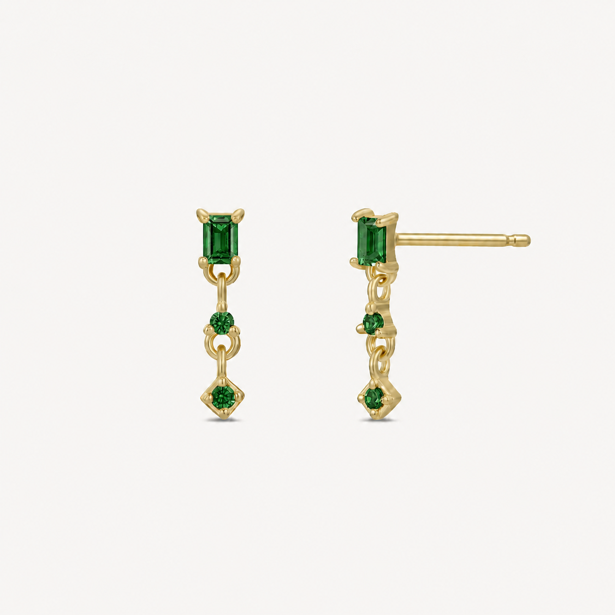 JaxKelly's Mini Baguette Drop Earrings - Emerald CZ feature gold-plated, hypoallergenic drops with a rectangular green stone above two smaller rounds, offering elegant comfort for daily wear against a white background.