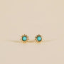 The Turquoise Sun Stud earrings feature 18k gold plating and a bold turquoise stone at the center, showcased against a plain beige background.