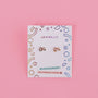 A pair of Bunny Enamel Flat Back Kids Earrings, small gold hypoallergenic studs shaped like bunnies, displayed on a white JaxKelly card with colorful designs and "Hypoallergenic" and "Kid-Friendly Posts" labels, set against a pink background.