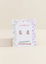 Boot Enamel Flat Back Kids Earrings in pink, shaped like cowboy boots with blue and yellow details. Displayed on a white JaxKelly card labeled "Hypoallergenic" and "Kid-friendly posts," with colorful geometric borders.