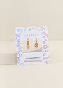 A pair of Bow Enamel Charm Hoop kids earrings with pink and yellow flower charms, displayed on a decorative JaxKelly card labeled Hypoallergenic and Kid-Friendly Posts.