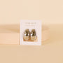 The Silver Bold Drop Earring features shiny, chunky statement hoops with sterling silver posts, displayed on a white JaxKelly card upright against a soft beige background.
